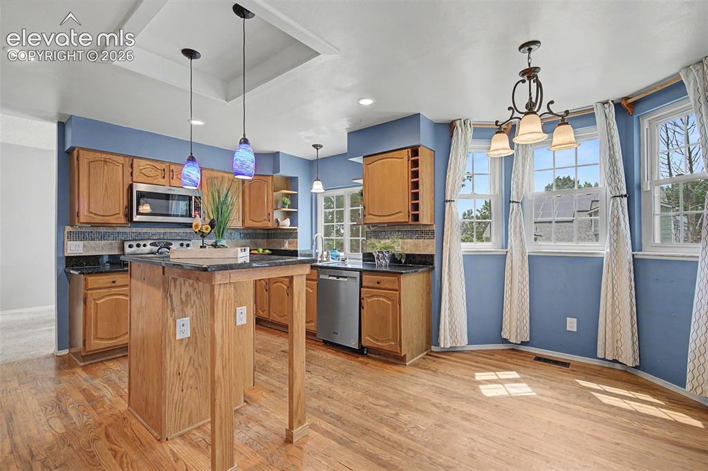 Image 9 of 42: Kitchen featuring wood-finish flooring, light wood cabinetry, and a central