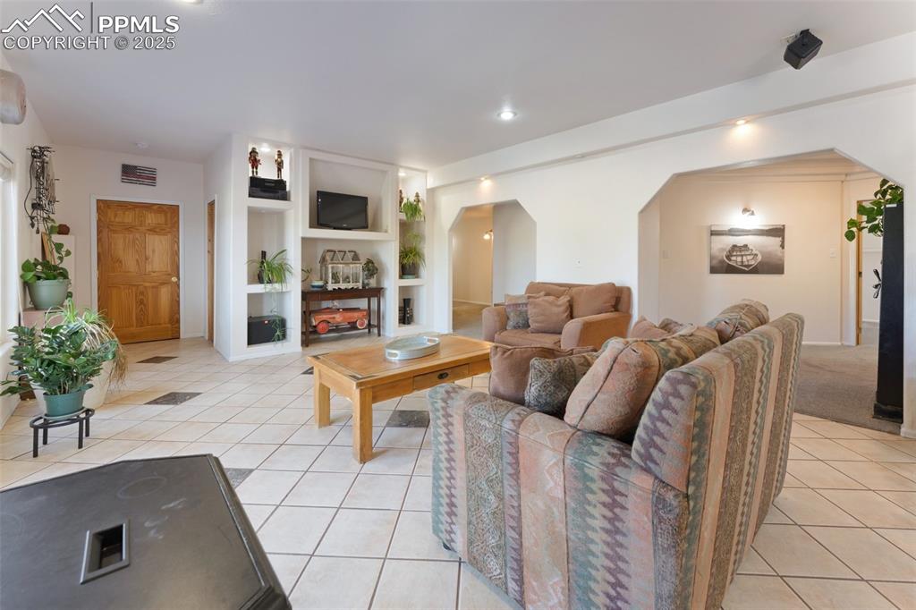 Image 35 of 44: Bright Basement Level Family Room with Built-Ins and Walkout to Concrete Pa