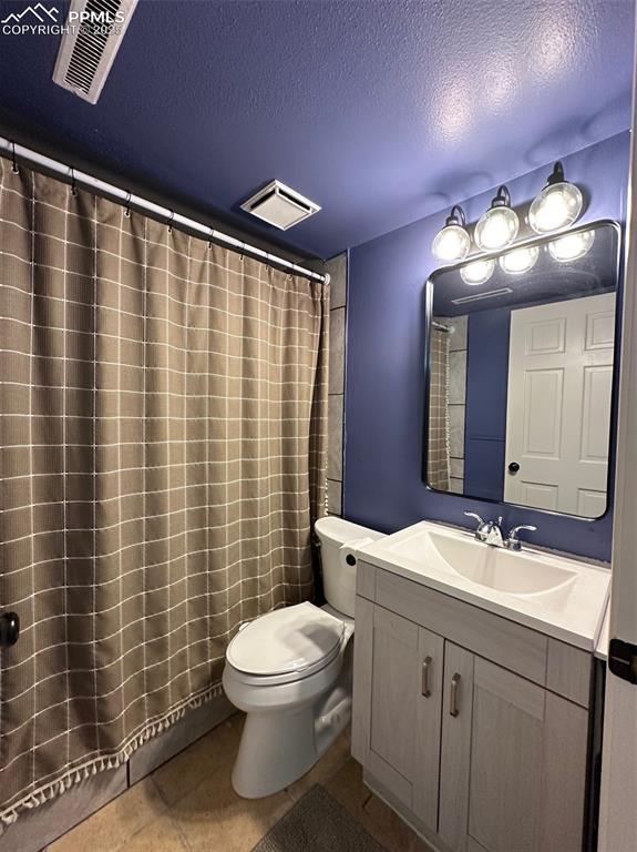 Image 10 of 14: Full bathroom featuring toilet, vanity, tile patterned floors, and a textur