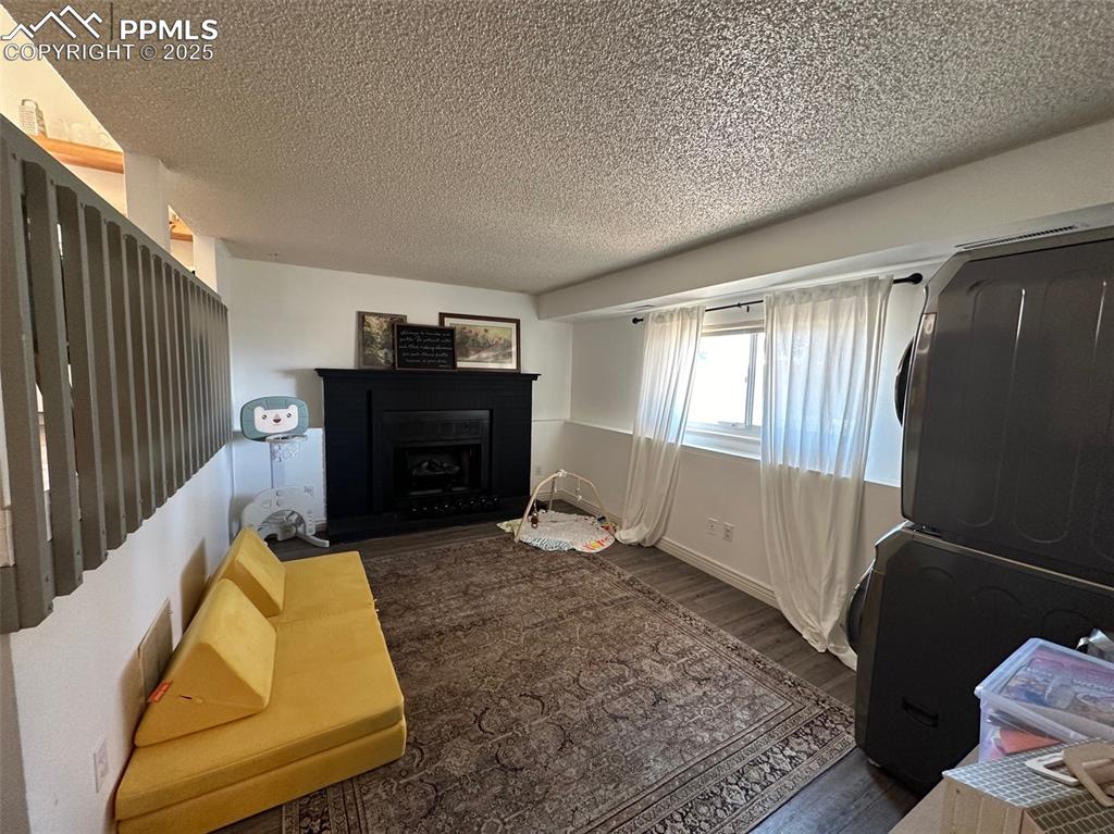 Image 13 of 14: Living room with a textured ceiling, wood finished floors, a fireplace, and