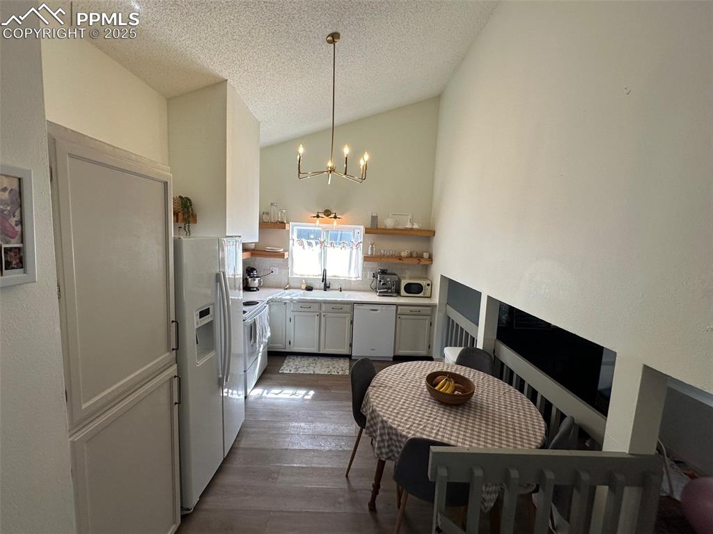 Image 3 of 14: Kitchen featuring white appliances, a chandelier, dark wood-style flooring,