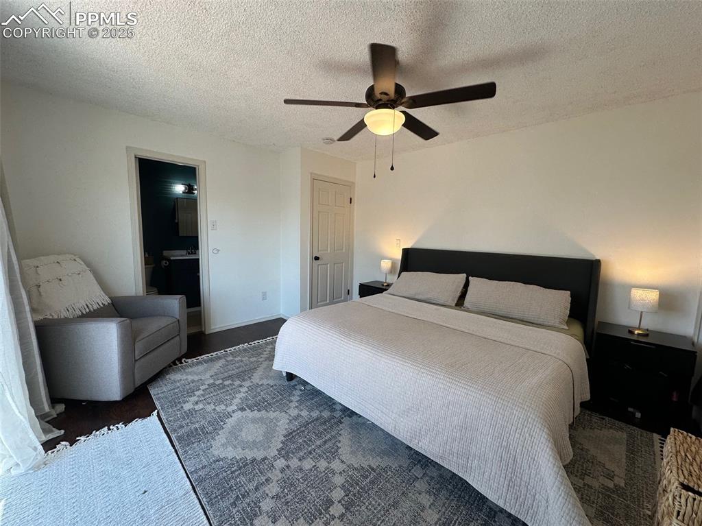 Image 7 of 14: Bedroom with a textured ceiling, a ceiling fan, ensuite bath, and wood fini