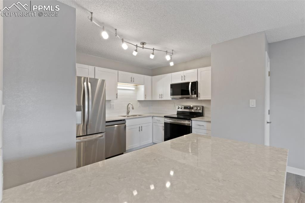 Image 7 of 15: Light & bright kitchen with bright quartz countertops and stainless steel a