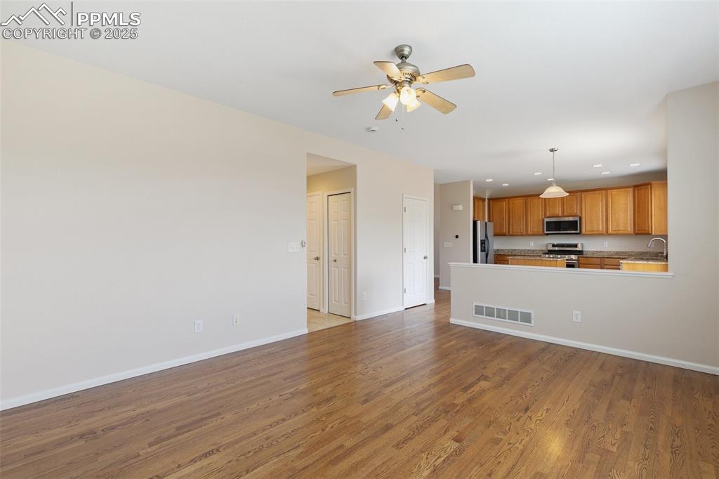 Image 15 of 45: Unfurnished living room with light wood finished floors, ceiling fan, and r