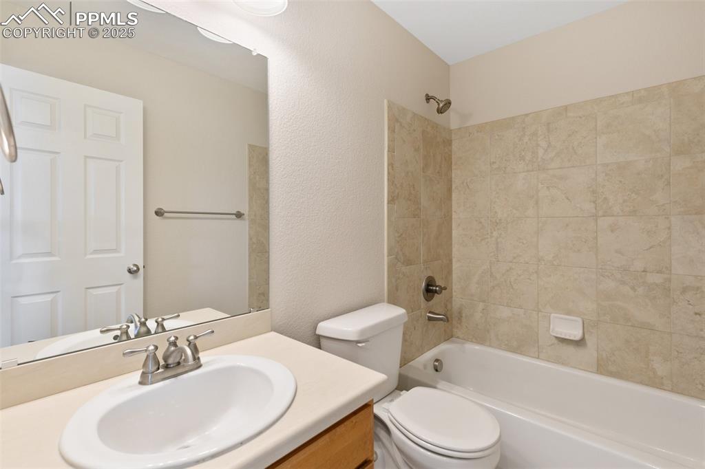 Image 21 of 45: Bathroom featuring vanity, shower / bathtub combination, and a textured wal