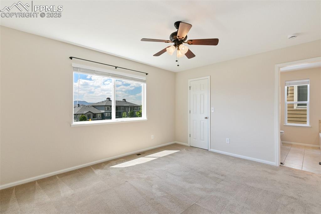 Image 24 of 45: Unfurnished bedroom with light colored carpet, ensuite bathroom, and a ceil