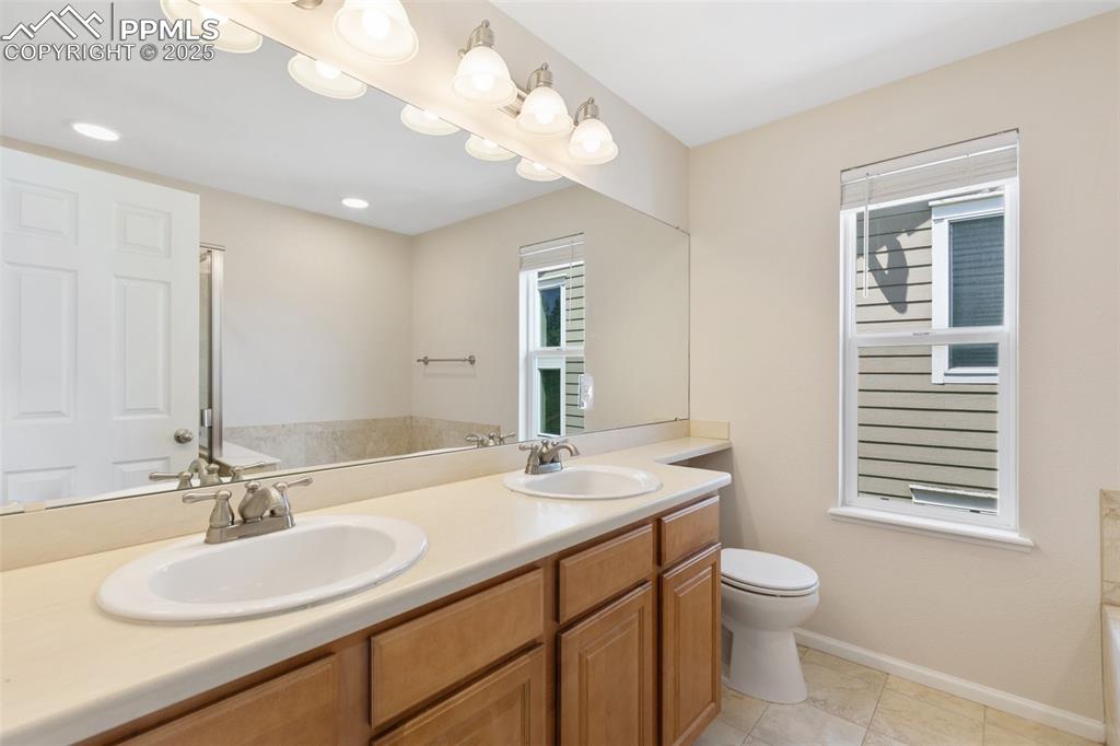 Image 31 of 45: Bathroom featuring double vanity, a tub to relax in, and tile patterned flo