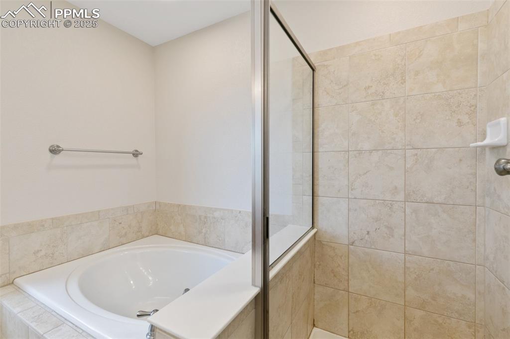 Image 32 of 45: Bathroom featuring a bath and a tile shower