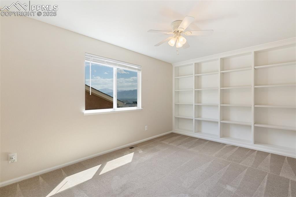 Image 33 of 45: Empty room featuring carpet floors, a ceiling fan, and built in features