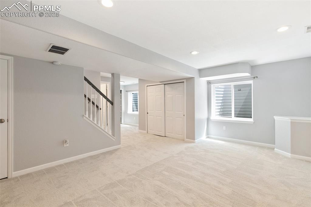Image 37 of 45: Below grade area with light colored carpet, stairs, and recessed lighting