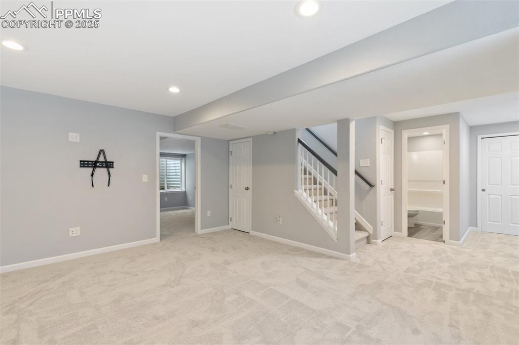 Image 38 of 45: Below grade area with light colored carpet, recessed lighting, and stairway