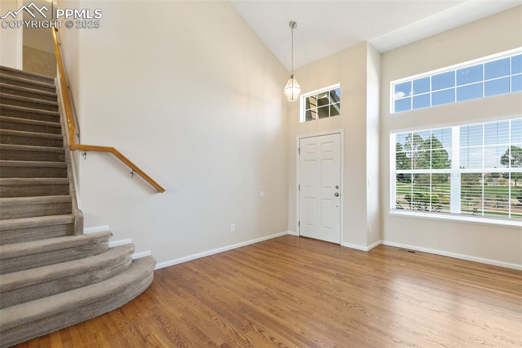 Image 6 of 45: Entrance foyer with stairway, wood finished floors, and high vaulted ceilin