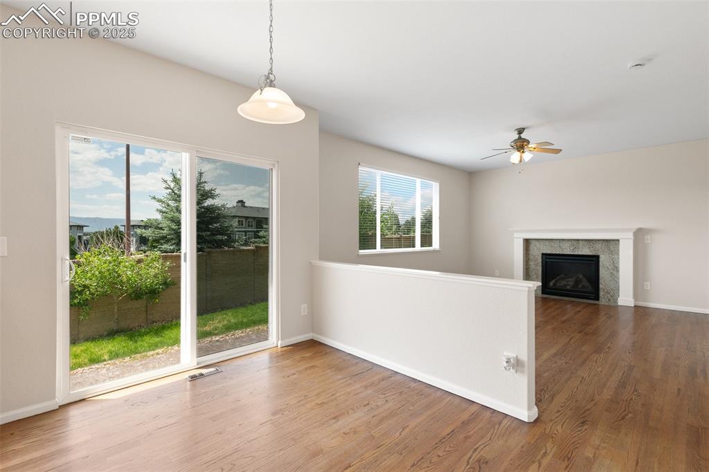 Image 9 of 45: Unfurnished living room with wood finished floors, ceiling fan, and a firep
