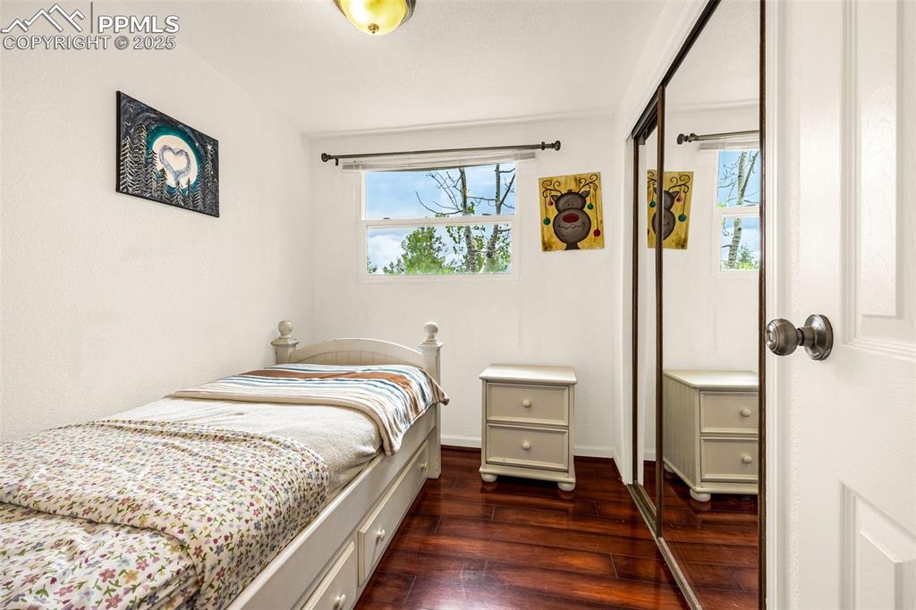 Image 12 of 31: Bedroom featuring dark wood-style flooring, multiple windows, and a closet