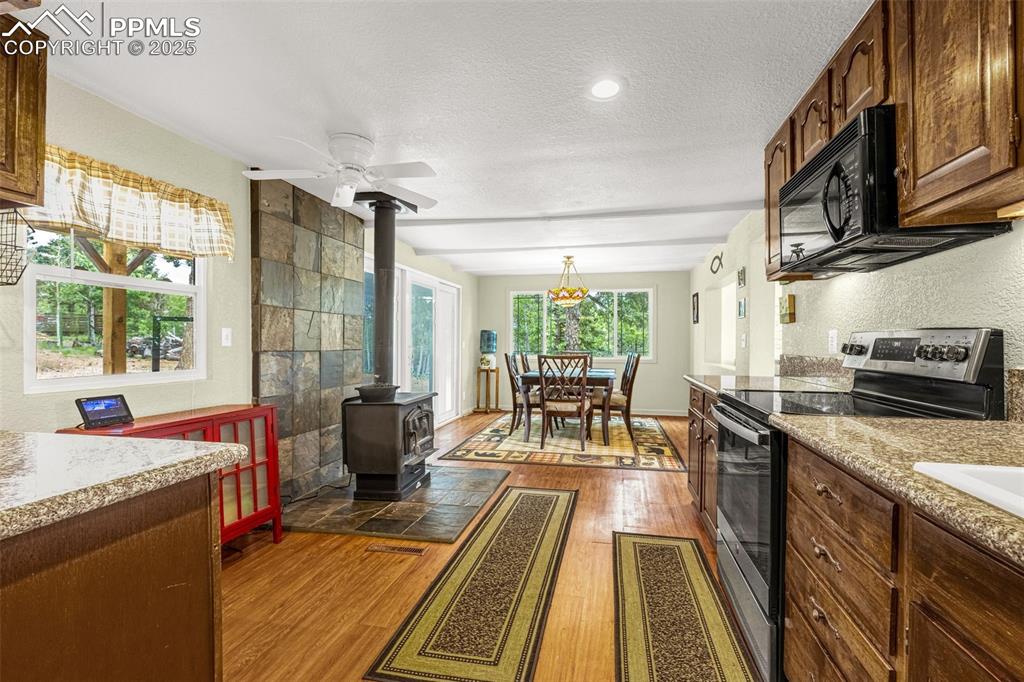 Image 7 of 31: Kitchen with stainless steel electric stove, a wood stove, black microwave,