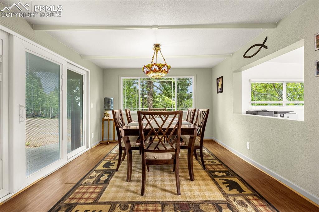 Image 9 of 31: Dining room featuring wood finished floors, beamed ceiling, and a textured 