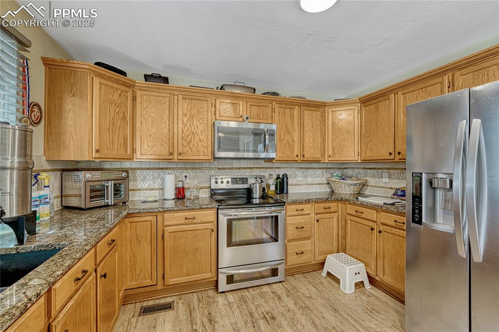 Image 10 of 31: Kitchen featuring appliances with stainless steel finishes, light wood fini