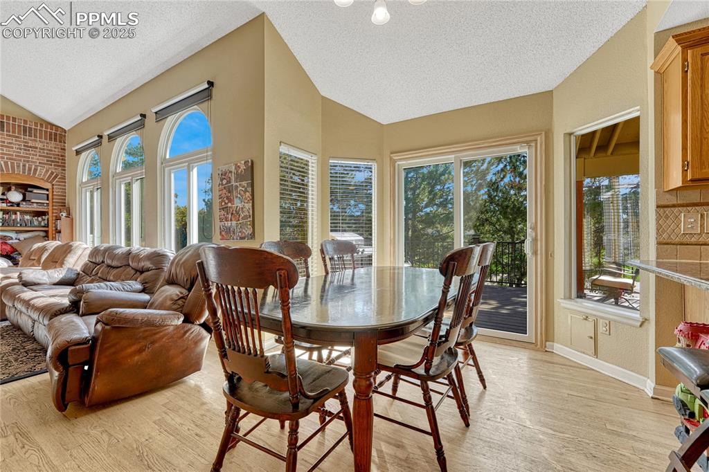 Image 11 of 31: Dining area with vaulted ceiling, light wood-style flooring, and a textured