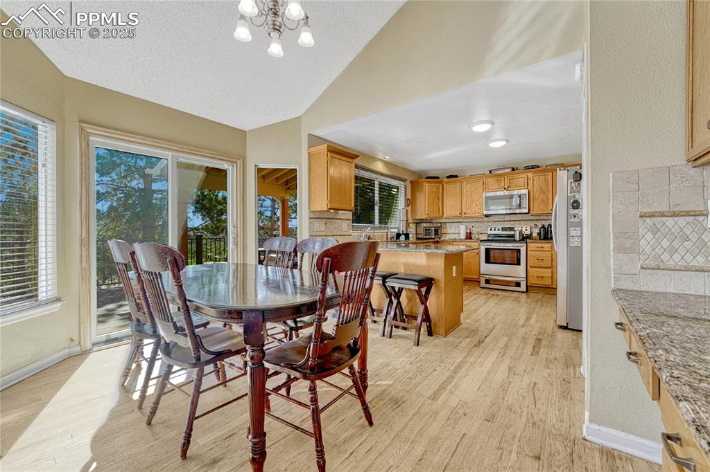 Image 12 of 31: Dining room featuring vaulted ceiling, light wood-type flooring, a chandeli