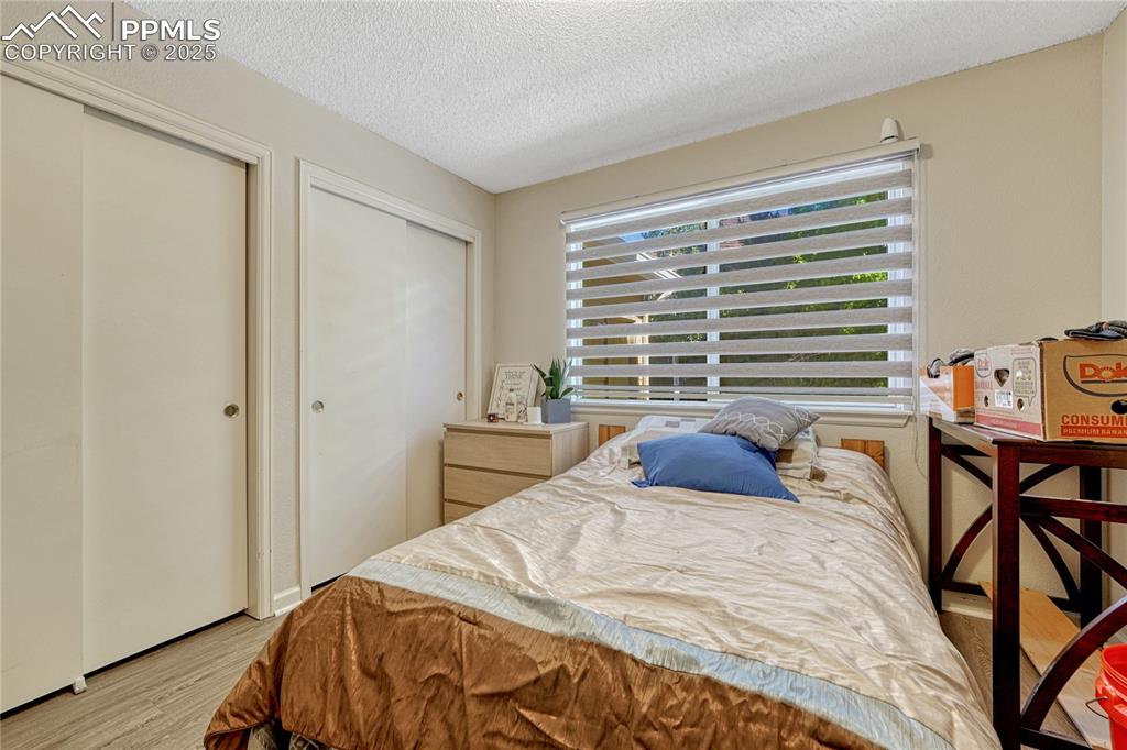 Image 18 of 31: Bedroom with light wood-style flooring, multiple closets, and a textured ce