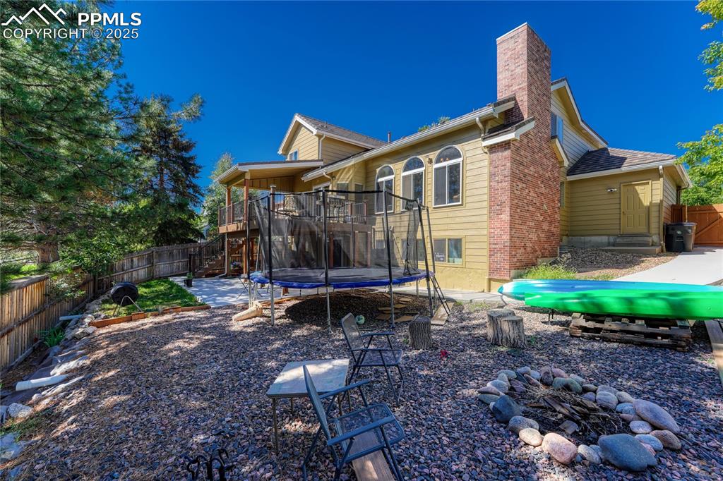 Image 30 of 31: Back of house featuring an outdoor fire pit, a chimney, a fenced backyard,