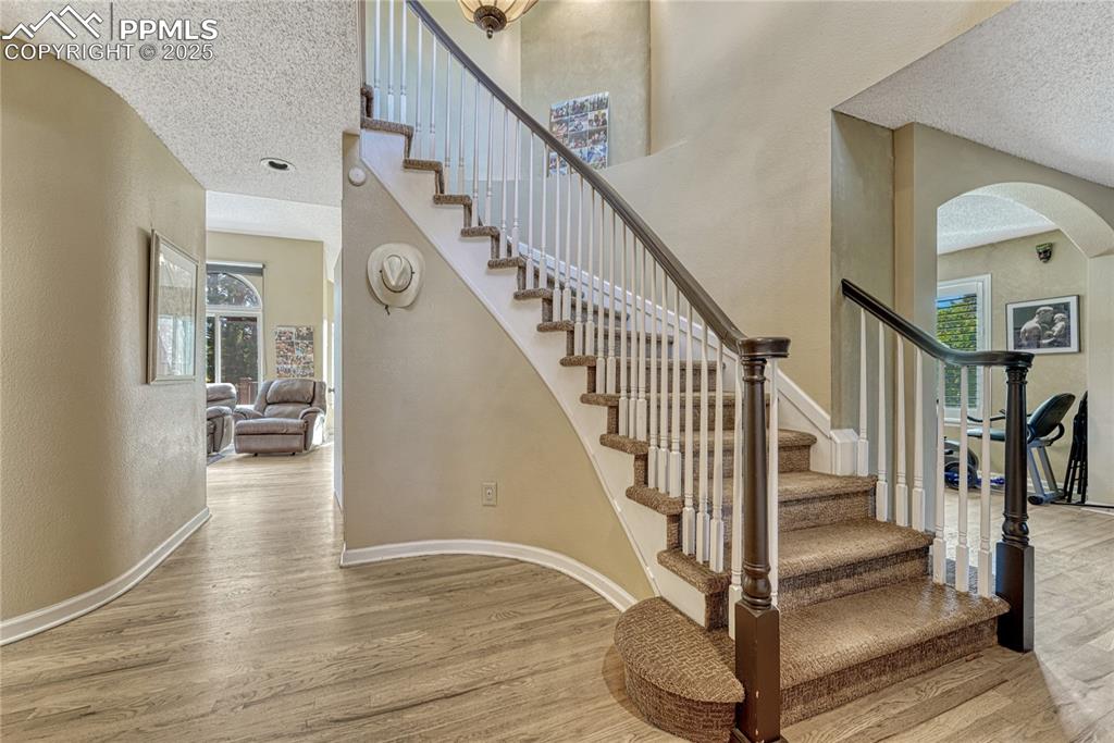 Image 6 of 31: Staircase featuring a textured ceiling, arched walkways, wood finished floo