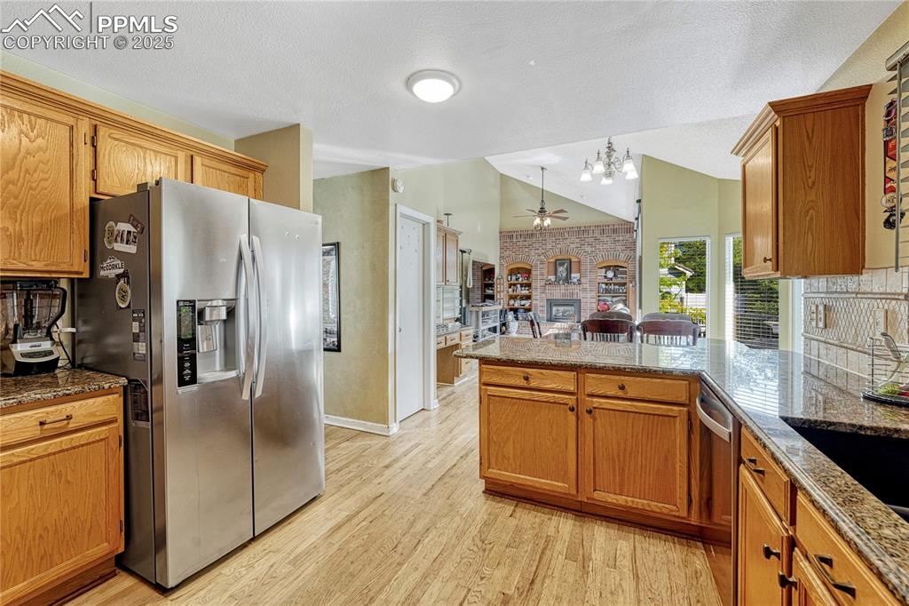 Image 9 of 31: Kitchen featuring backsplash, stainless steel appliances, dark stone counte