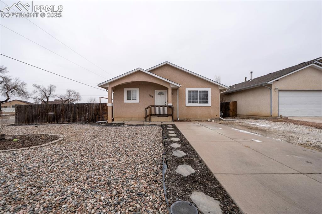 Caption: View of front of property with fence and stucco siding