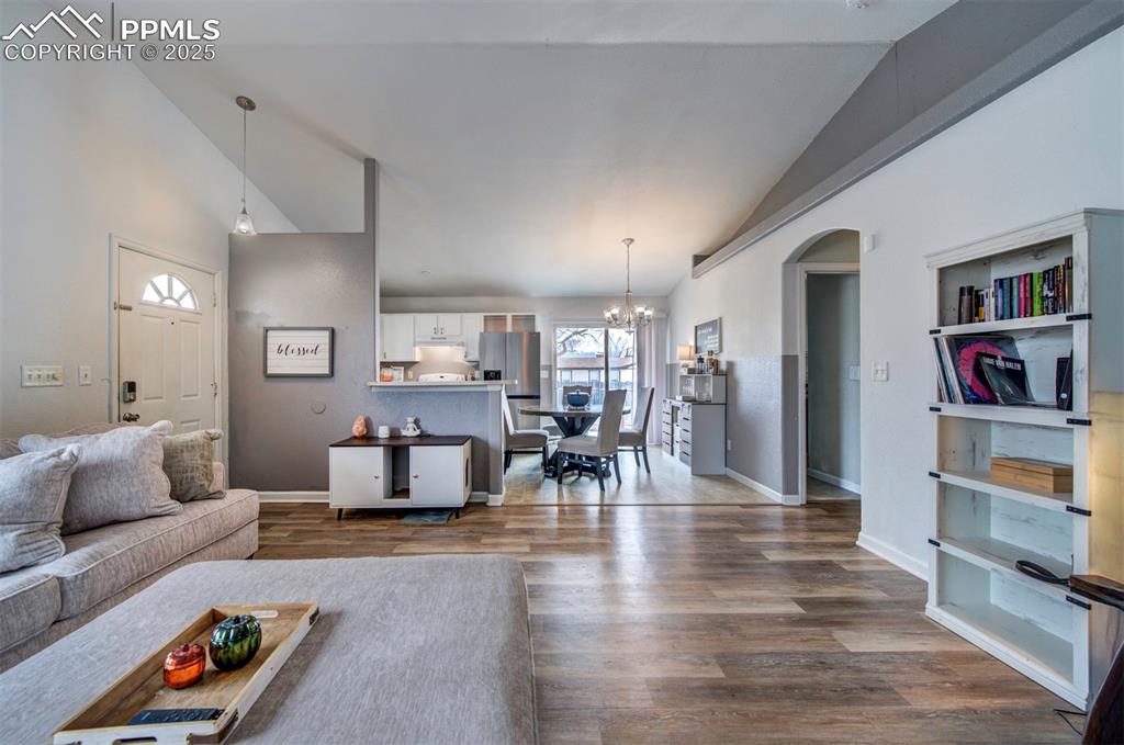Image 11 of 25: Living area featuring baseboards, high vaulted ceiling, arched walkways, da