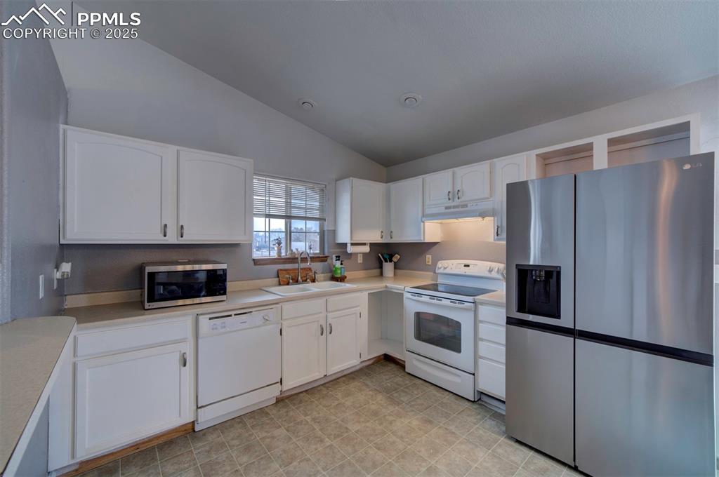 Image 16 of 25: Kitchen featuring a sink, white cabinets, under cabinet range hood, and sta