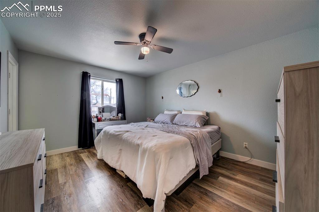 Image 18 of 25: Bedroom featuring ceiling fan, wood finished floors, baseboards, and a text