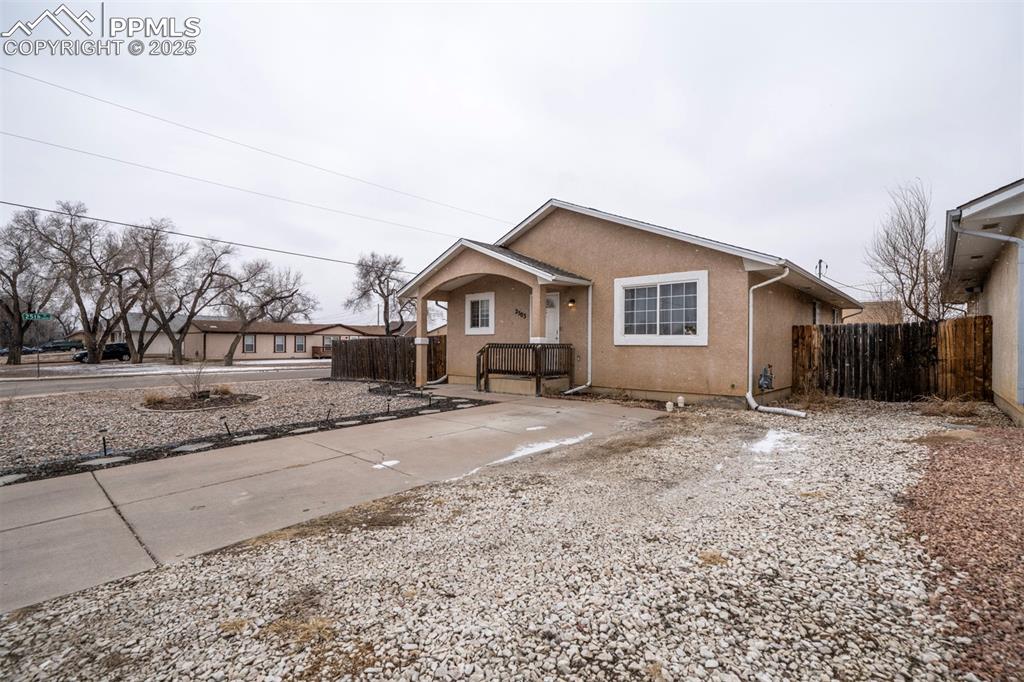 Image 2 of 25: View of front of house with stucco siding and fence