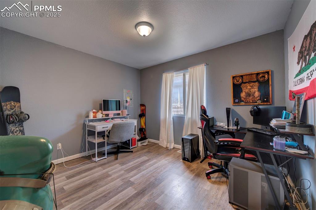Image 21 of 25: Office space with a textured ceiling, baseboards, and wood finished floors