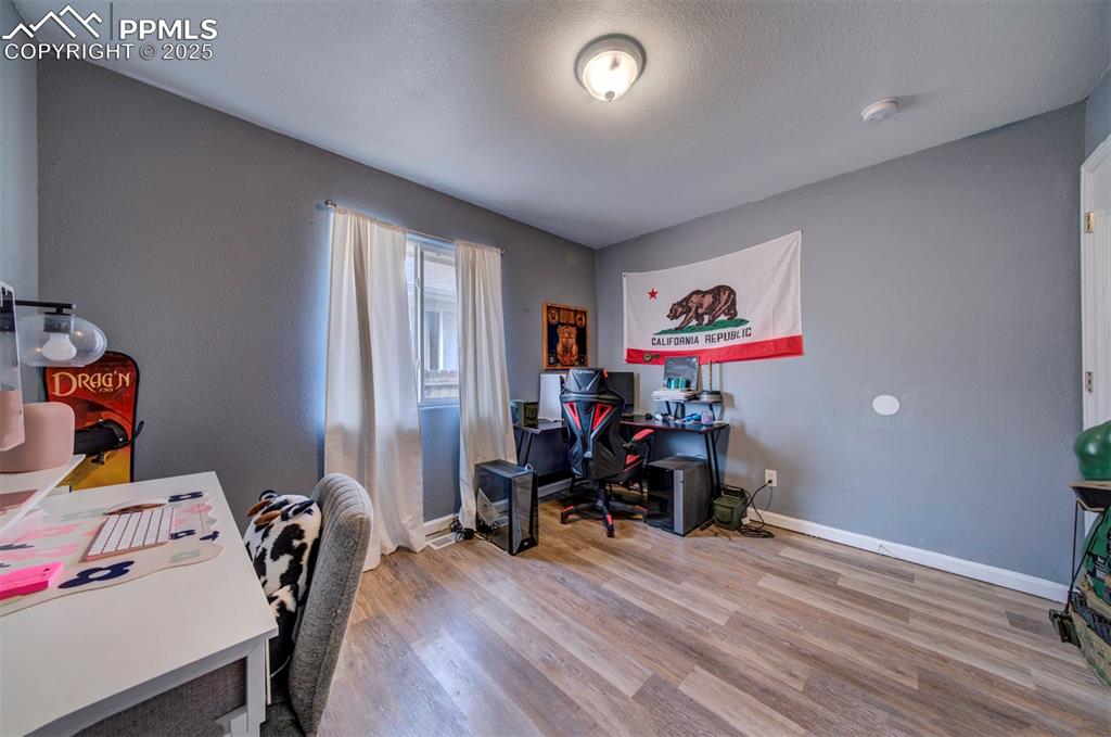 Image 22 of 25: Home office featuring baseboards, a textured ceiling, and wood finished flo
