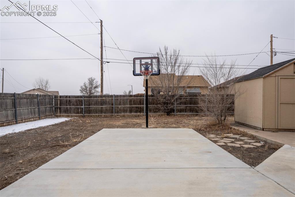 Image 3 of 25: View of sport court with a storage shed and a fenced backyard