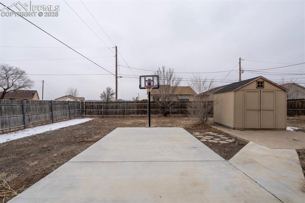 Image 4 of 25: View of patio featuring an outbuilding, a shed, and a fenced backyard
