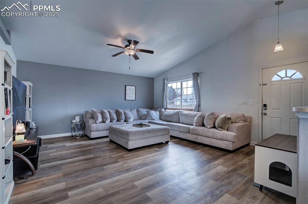 Image 8 of 25: Living room with ceiling fan, baseboards, and lofted ceiling