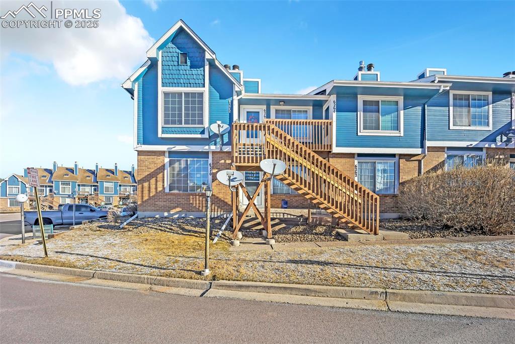 Image 10 of 13: View of front facade with stairway, brick siding, and a residential view