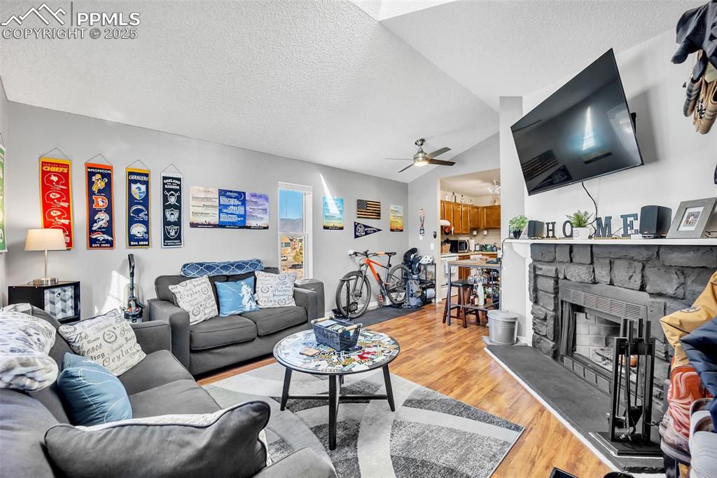 Image 2 of 13: Living room with light wood-style flooring, a textured ceiling, vaulted cei