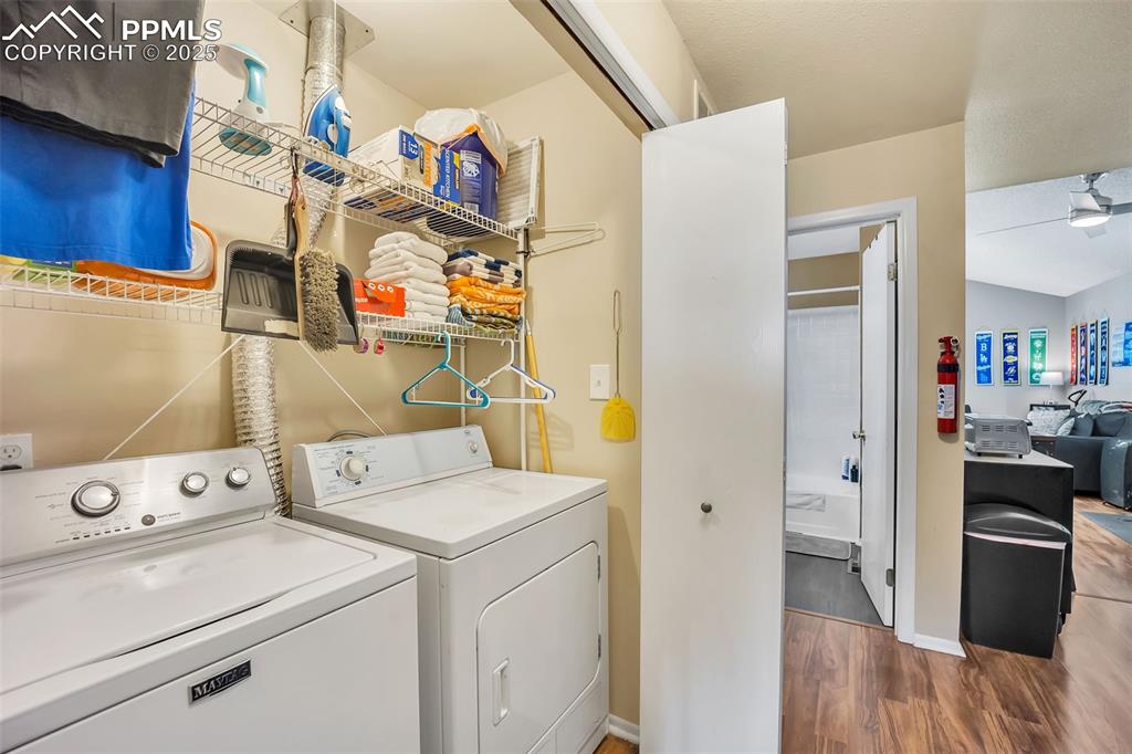 Image 4 of 13: Washroom featuring wood finished floors and washing machine and dryer