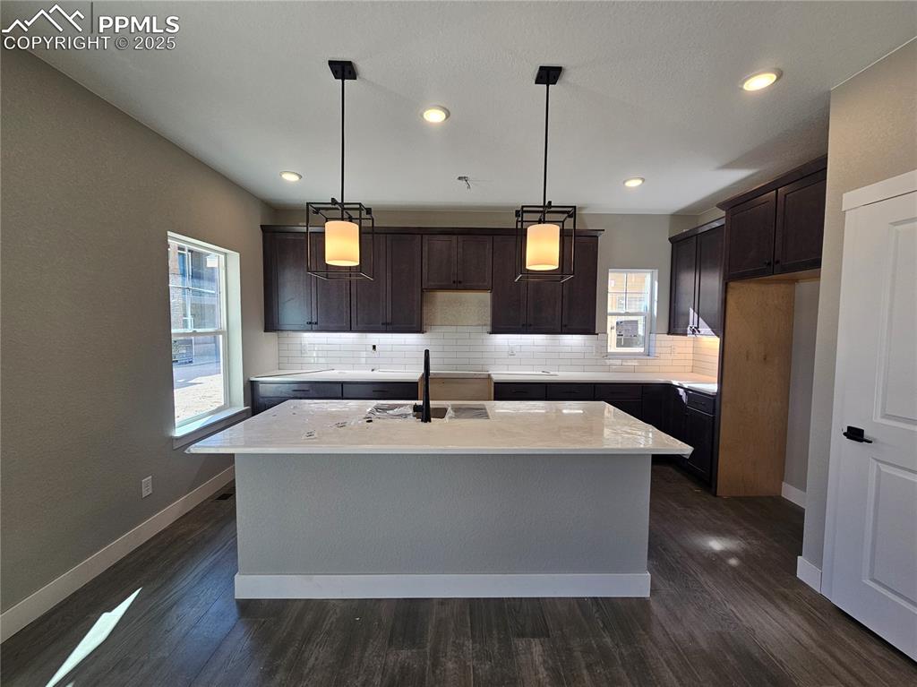 Image 3 of 12: Kitchen with pendant lighting, dark brown cabinetry, a center island with s