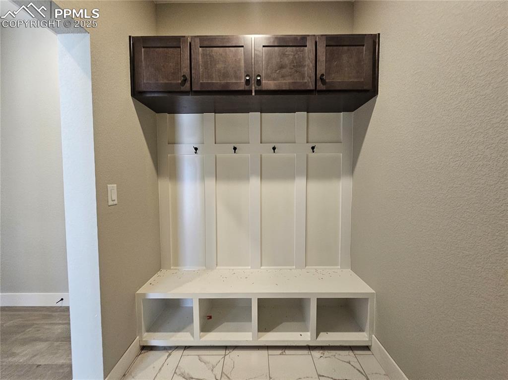 Image 5 of 12: Mudroom with a textured wall and light marble finish floors