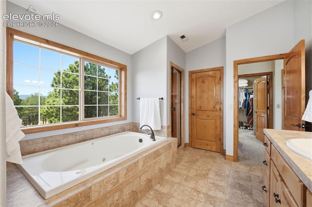 Image 17 of 50: Double vanity with wood-finish cabinetry and tile countertops