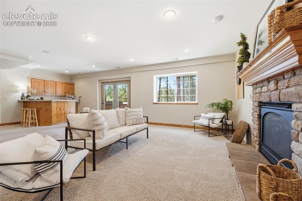 Image 24 of 50: Spacious room featuring carpeting, recessed lighting, and a stone fireplace