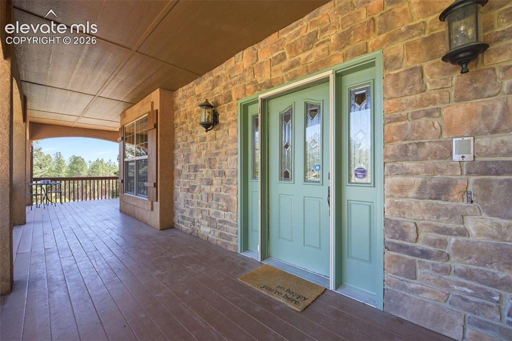 Image 35 of 50: Stucco exterior featuring a stone accent façade and a full-width covered po
