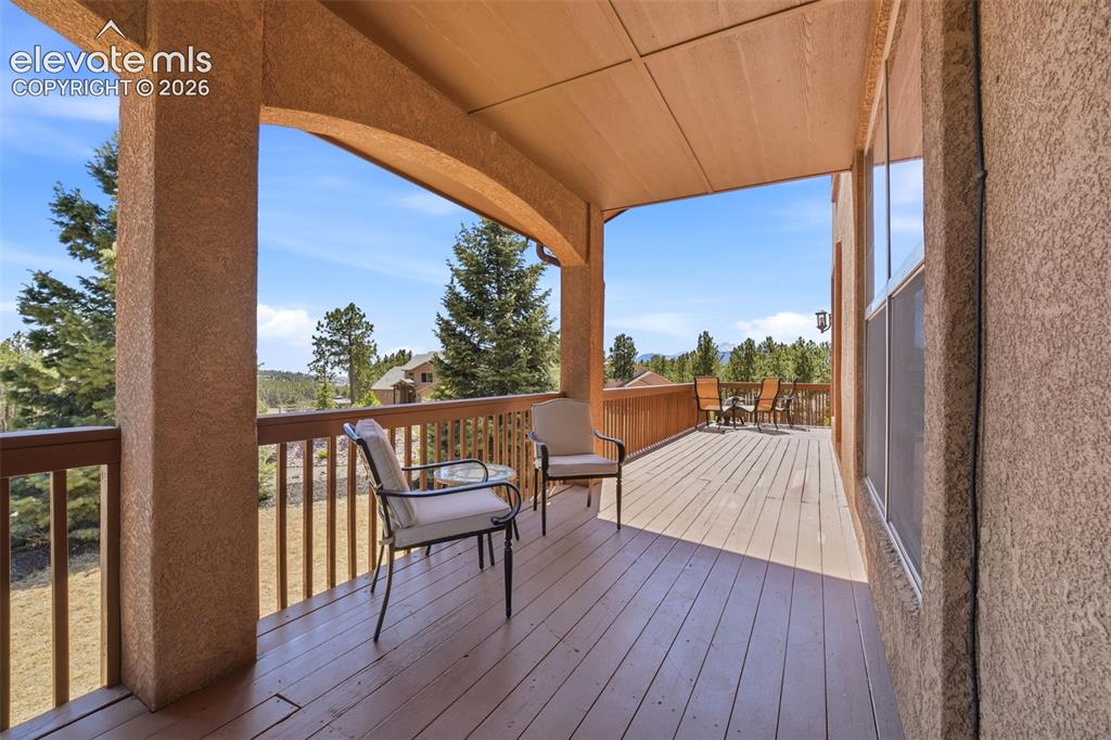 Image 39 of 50: Expansive wood-finish deck with a covered portion, featuring a stucco exter