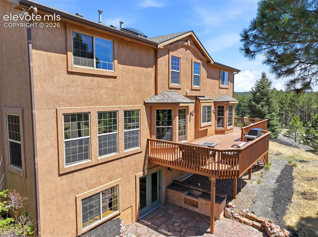 Image 44 of 50: Stucco exterior residence featuring a multi-level wooden deck with integrat