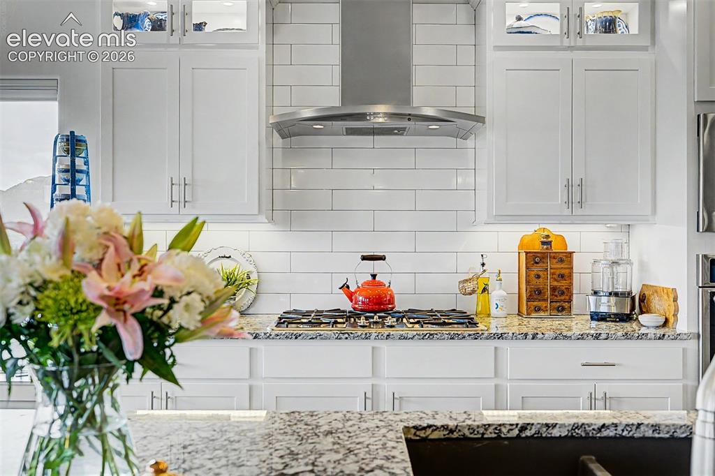 Image 18 of 49: Gorgeous subway tiling, custom hooded vent, and a great gas stove top!