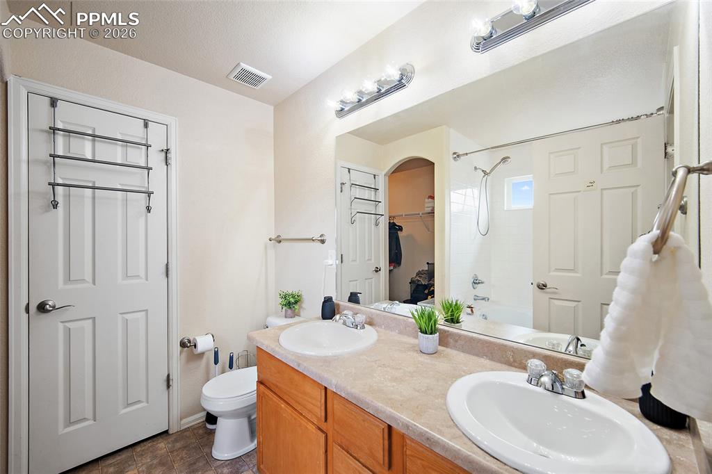 Image 18 of 43: Bathroom featuring a dual-sink vanity with a laminate countertop, wood-fini