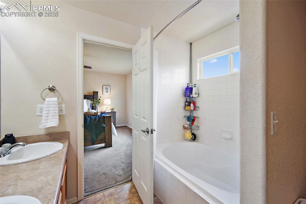 Image 19 of 43: Bathroom featuring a combination tub and shower with white subway tile surr